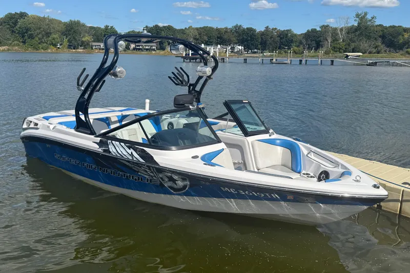 The Image of 2000 Correct Craft Super Air Nautique boat docked on a sunny lake. - 0