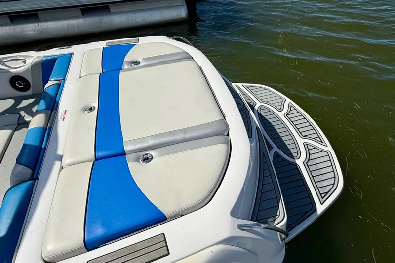 Slide: The Image of 2000 Correct Craft Super Air Nautique boat with blue and white seating, docked on water. - 12