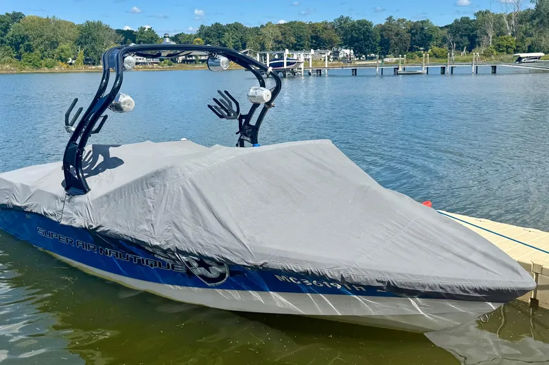 Slide: The Image of Covered 2000 Correct Craft Super Air Nautique boat docked on a calm lake. - 14