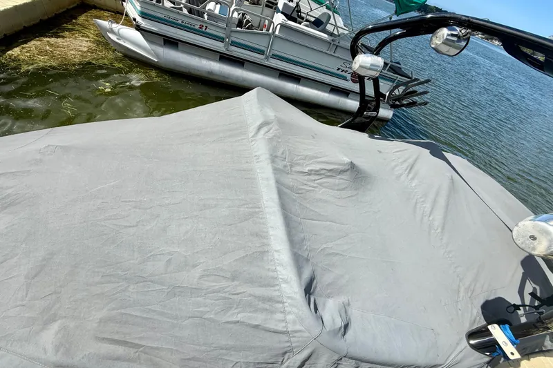 Slide: The Image of Covered 2000 Correct Craft Super Air Nautique boat docked beside a pontoon on a lake. - 16