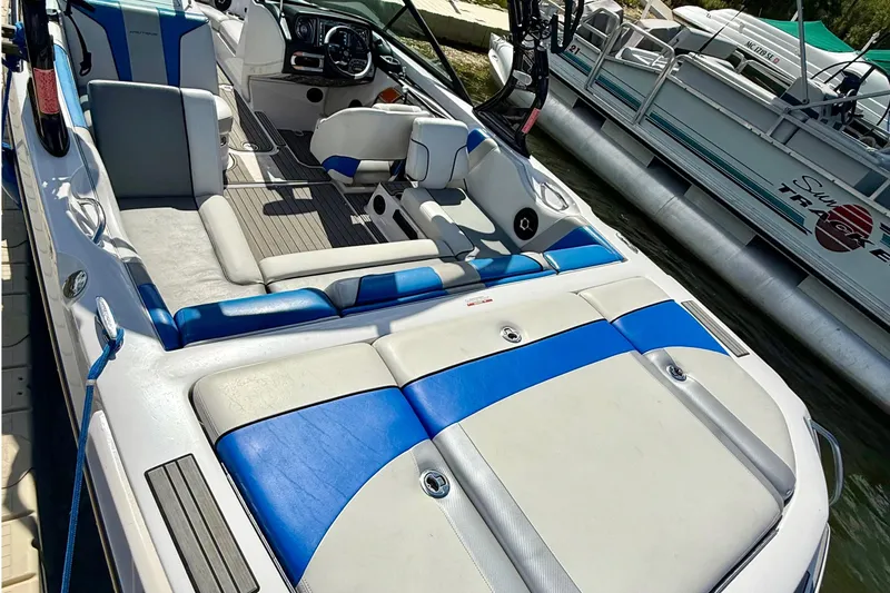Slide: The Image of 2000 Correct Craft Super Air Nautique boat interior with blue and white seating, docked beside another vessel. - 8