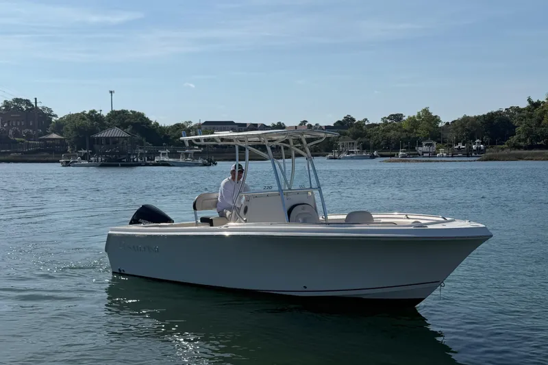 Slide: The Image of 2023 Sailfish 220 CC boat on calm water near a marina. - 10