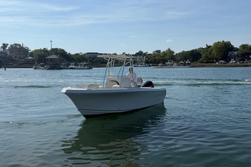 Slide: The Image of 2023 Sailfish 220 CC boat cruising on a calm river with scenic background. - 11