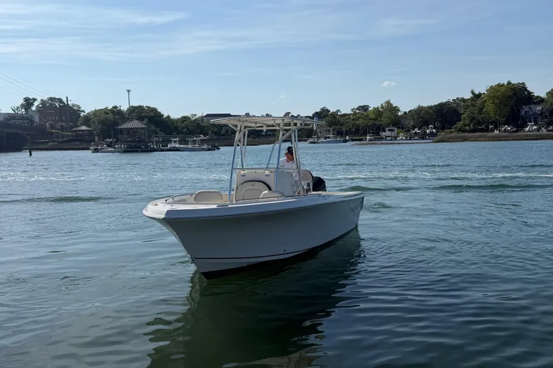 Slide: The Image of 2023 Sailfish 220 CC boat cruising on a calm river with scenic background. - 12