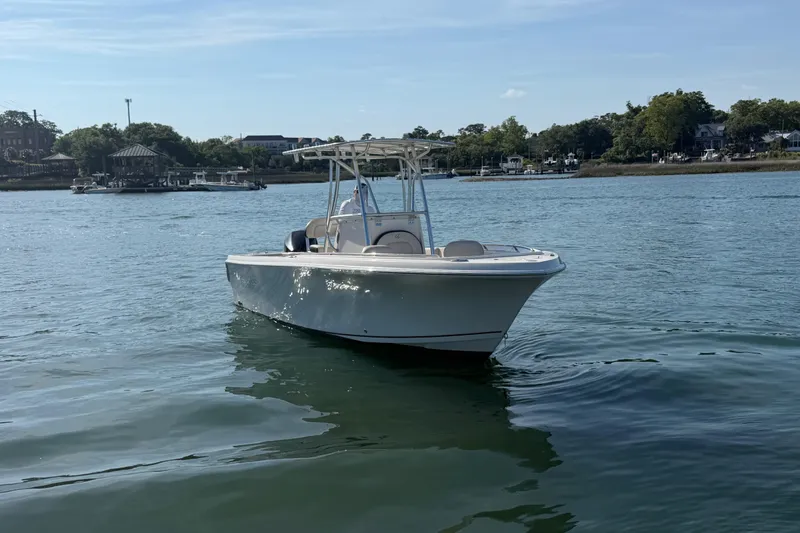 Slide: The Image of 2023 Sailfish 220 CC boat on calm water with scenic shoreline background. - 13