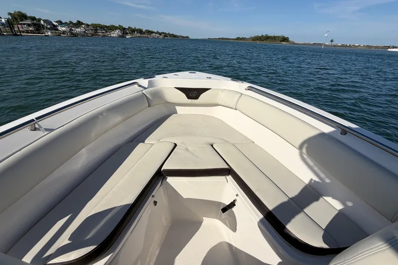 Slide: The Image of 2023 Sailfish 220 CC boat interior with cushioned seating on calm water. - 19