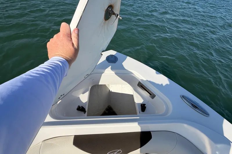 Slide: The Image of 2023 Sailfish 220 CC boat with open storage compartment on calm water. - 20