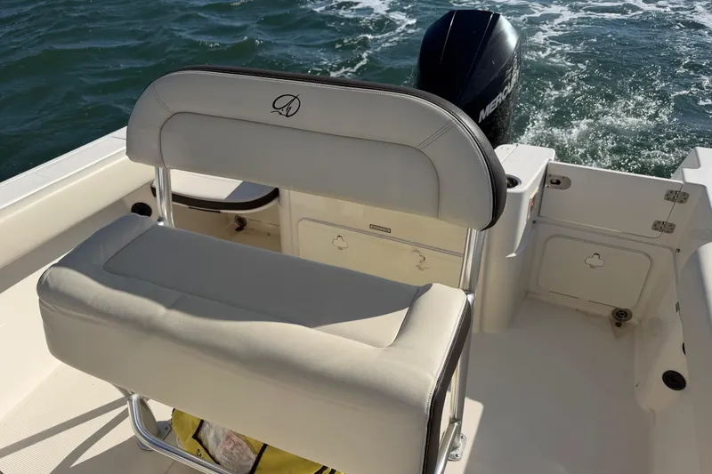 Slide: The Image of 2023 Sailfish 220 CC boat interior with cushioned seating and outboard motor on water. - 30
