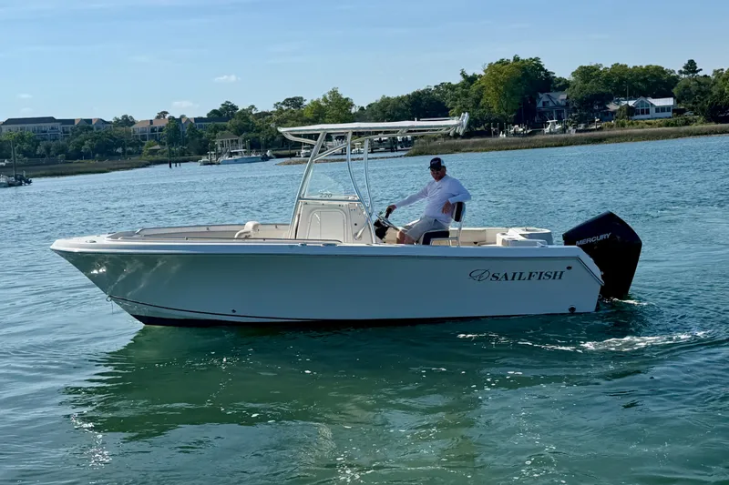 Slide: The Image of 2023 Sailfish 220 CC boat cruising on a calm lake with a Mercury engine. - 5
