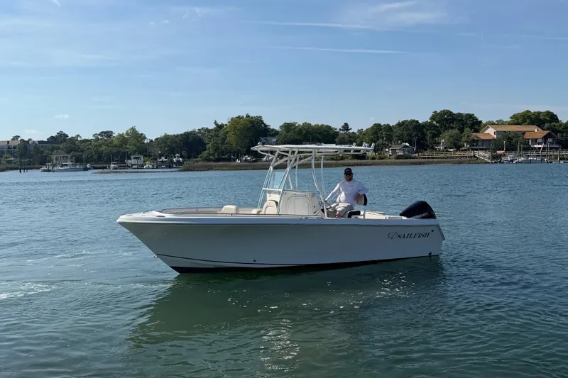 Slide: The Image of 2023 Sailfish 220 CC boat on calm water with scenic shoreline background. - 6