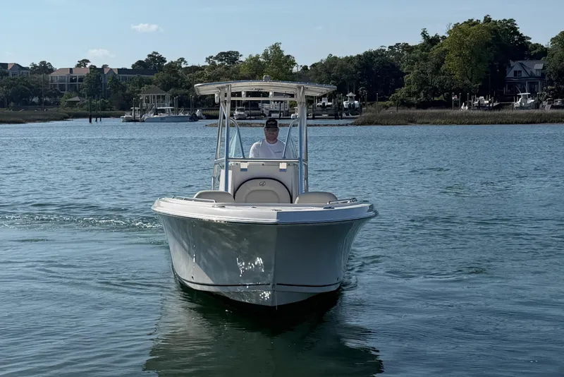 Slide: The Image of 2023 Sailfish 220 CC boat cruising on a calm lake with scenic background. - 8