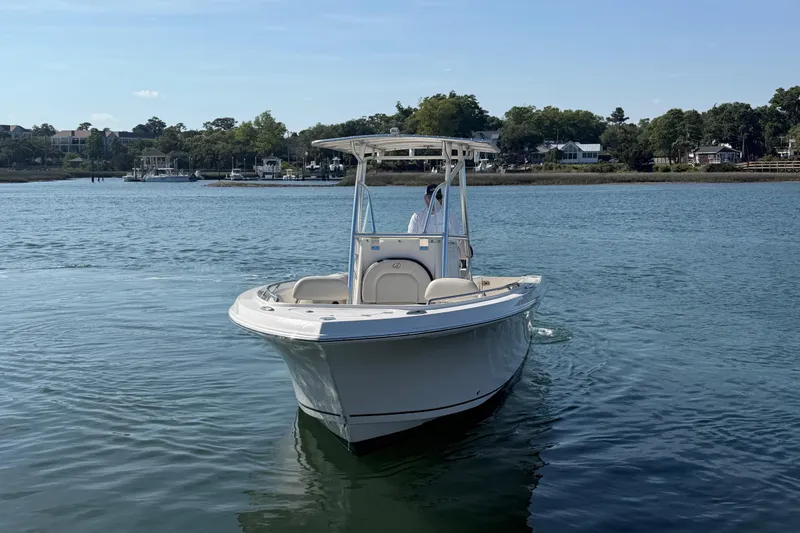 Slide: The Image of 2023 Sailfish 220 CC boat cruising on a calm lake with scenic shoreline. - 9