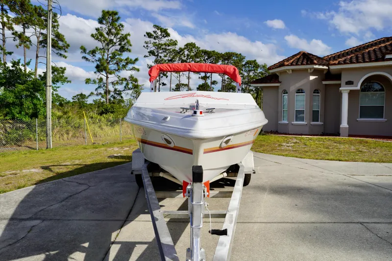 Slide: The Image of 1996 Baja 20 Outlaw boat on trailer, parked in driveway near house, under blue sky. - 4