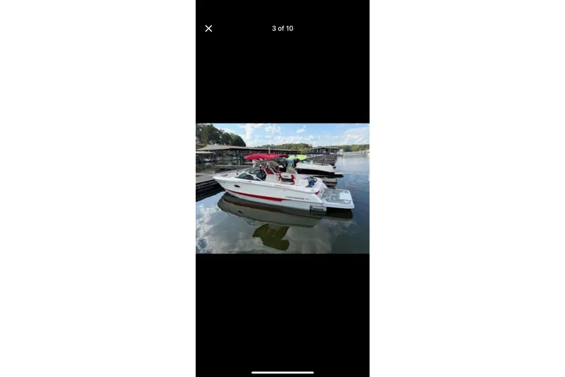 Slide: The Image of 2020 Chaparral 25 Surf boat docked on a calm lake with a red canopy. - 3