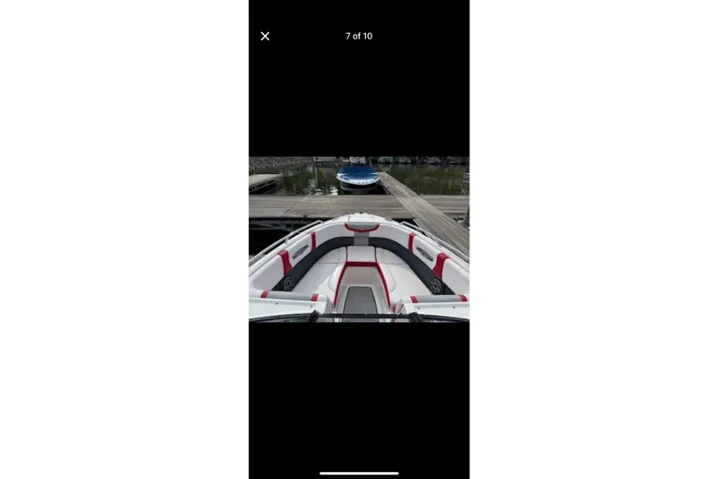 Slide: The Image of 2020 Chaparral 25 Surf boat interior with red and gray seating at a dock. - 4