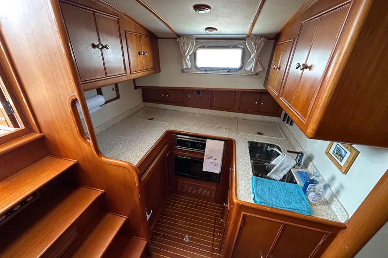 Slide: The Image of 2003 Grand Banks 43 Eastbay HX yacht kitchen with wooden cabinets and compact appliances. - 22