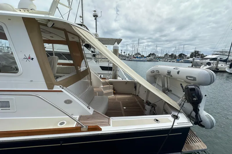Slide: The Image of 2003 Grand Banks 43 Eastbay HX yacht docked with inflatable boat and wooden deck. - 7