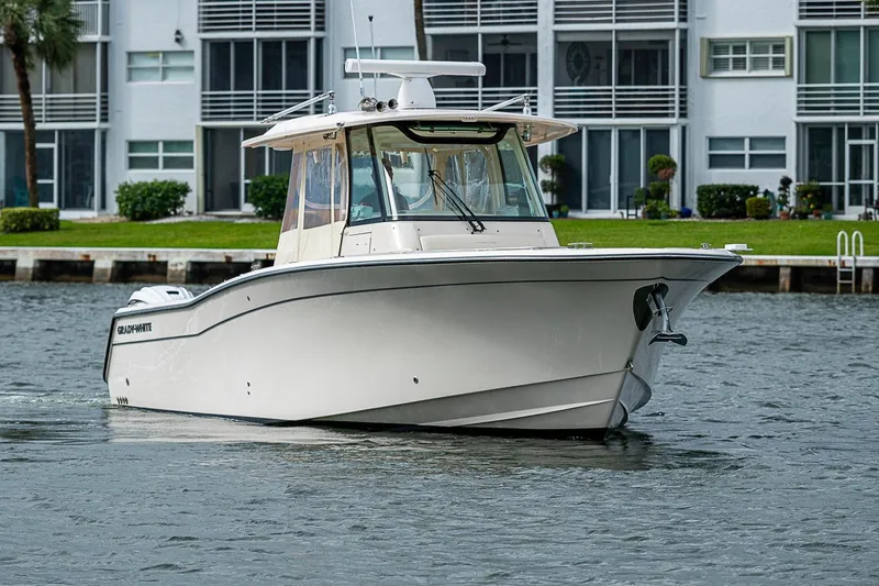 Slide: The Image of 2020 Grady-White Canyon 336 boat cruising near waterfront buildings. - 9
