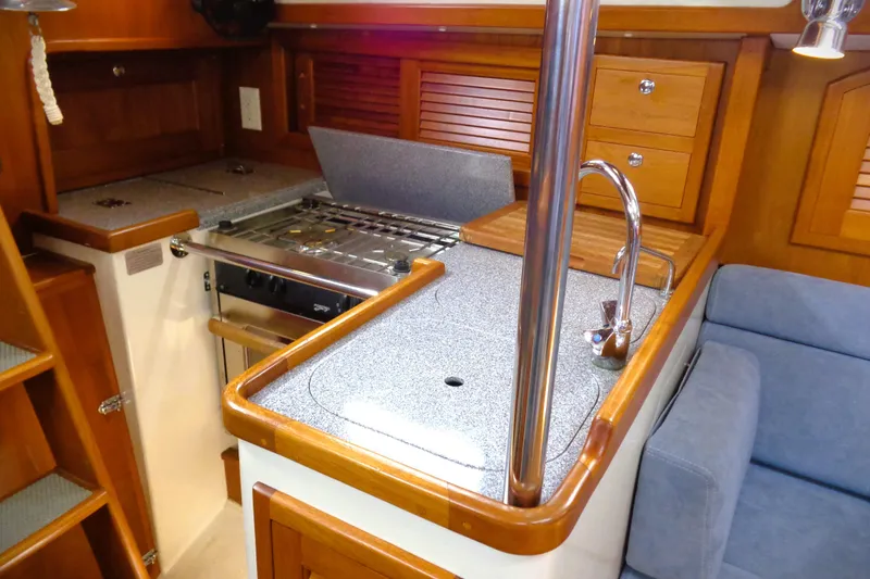 Slide: The Image of Interior of 2009 Pacific Seacraft 34 sailboat, featuring a compact kitchen with wooden cabinetry. - 4