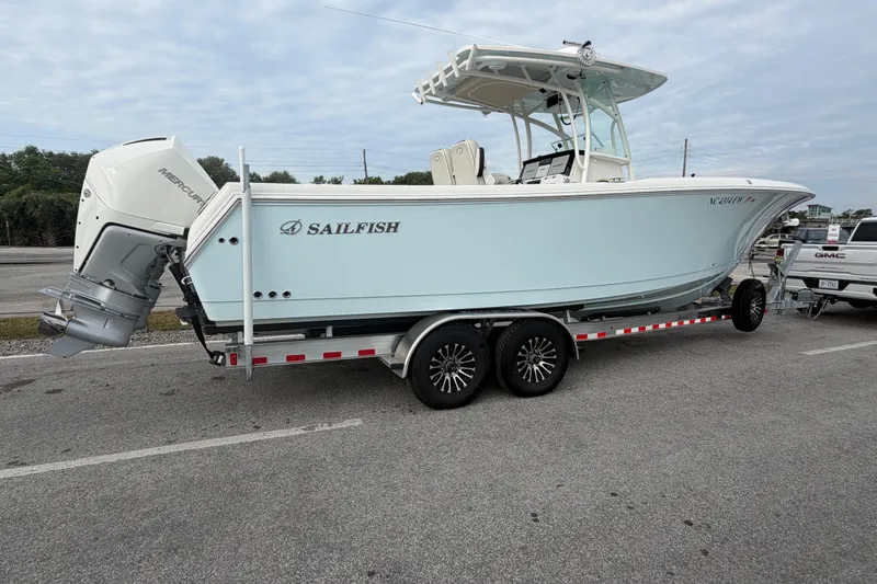 Slide: The Image of 2021 Sailfish 290 CC boat on trailer, featuring Mercury outboard engine, parked outdoors. - 12