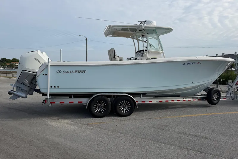 Slide: The Image of 2021 Sailfish 290 CC boat on trailer, parked in a lot under cloudy sky. - 16