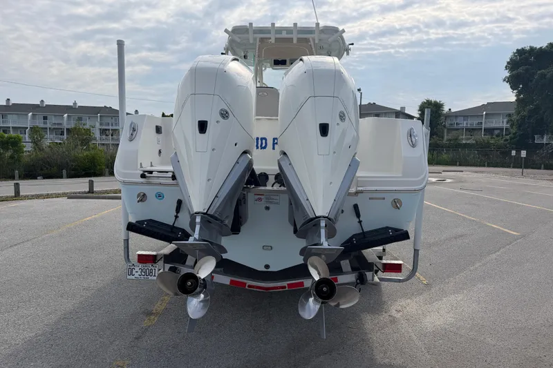 Slide: The Image of 2021 Sailfish 290 CC boat with dual outboard motors in a parking lot. - 17