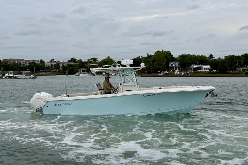 Slide: The Image of 2021 Sailfish 290 CC boat cruising on a calm waterway with scenic shoreline. - 2