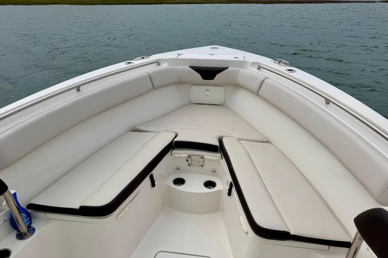 Slide: The Image of 2021 Sailfish 290 CC boat interior with cushioned seating and cup holders on calm water. - 25