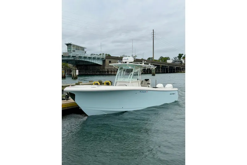 Slide: The Image of 2021 Sailfish 290 CC boat docked near a bridge on a cloudy day. - 3