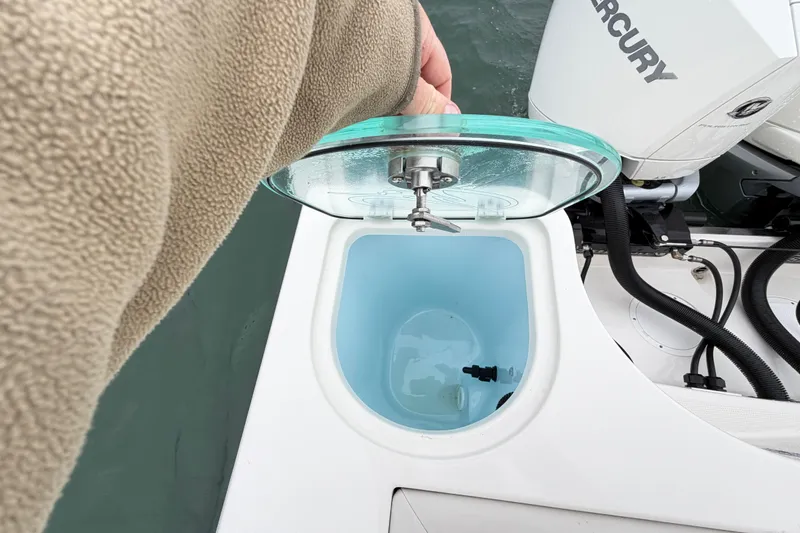 Slide: The Image of Open hatch on 2021 Sailfish 290 CC boat, revealing storage compartment near Mercury engine. - 38