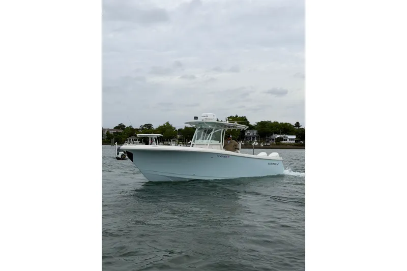 Slide: The Image of 2021 Sailfish 290 CC boat cruising on a calm waterway under cloudy skies. - 4