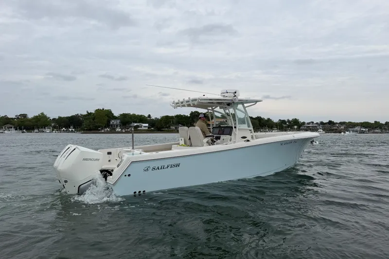 Slide: The Image of 2021 Sailfish 290 CC boat cruising on a calm lake with scenic shoreline. - 43