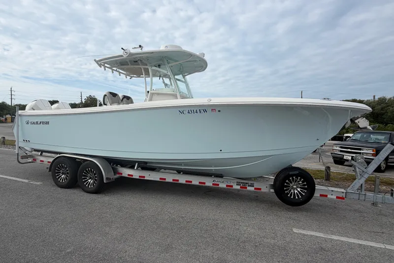 Slide: The Image of 2021 Sailfish 290 CC boat on trailer, parked outdoors under cloudy sky. - 6
