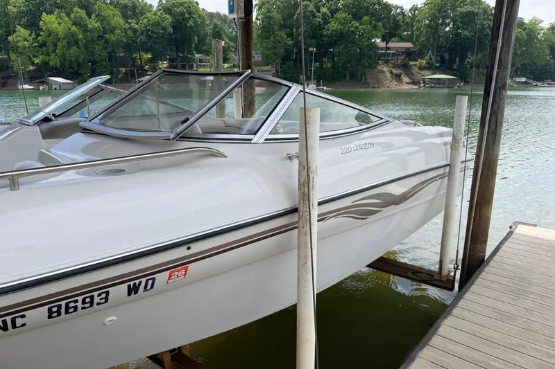 Slide: The Image of 1998 Four Winns 220 Horizon boat docked on a serene lake with lush greenery. - 19