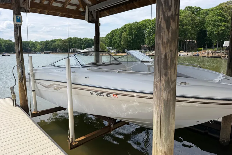 Slide: The Image of 1998 Four Winns 220 Horizon boat docked on a lift by a scenic lake. - 22