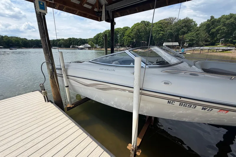 Slide: The Image of 1998 Four Winns 220 Horizon boat docked on a lake under a wooden shelter. - 23