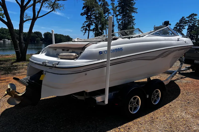 Slide: The Image of 1998 Four Winns 220 Horizon boat on trailer by a lakeside, under clear blue sky. - 3