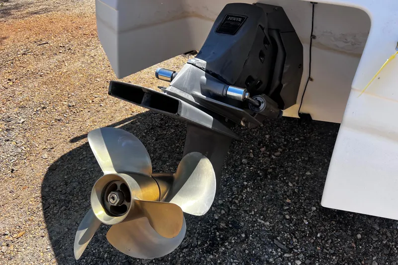 Slide: The Image of 1998 Four Winns 220 Horizon boat propeller and outdrive on gravel surface. - 5