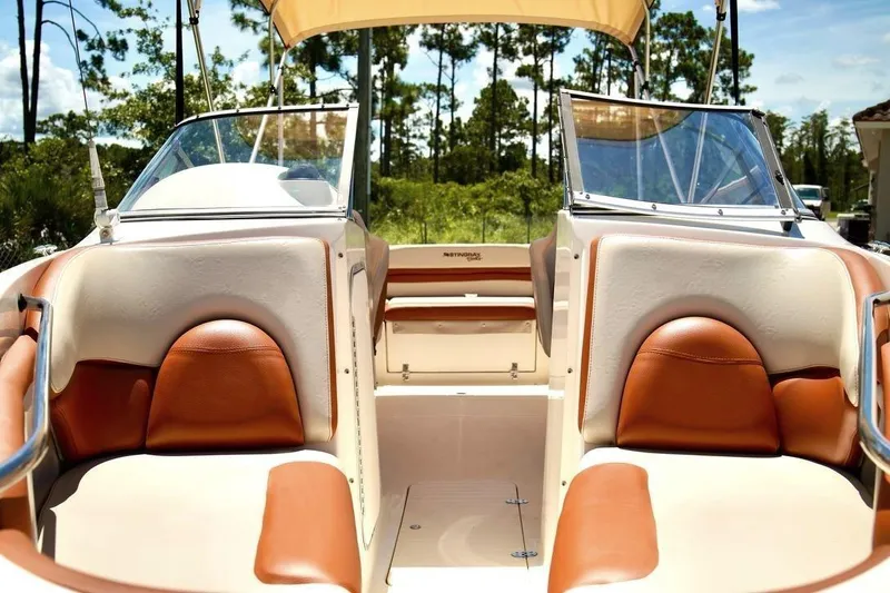 Slide: The Image of 2001 Stingray 240 LS boat interior with tan and brown seating, sunny outdoor setting. - 10
