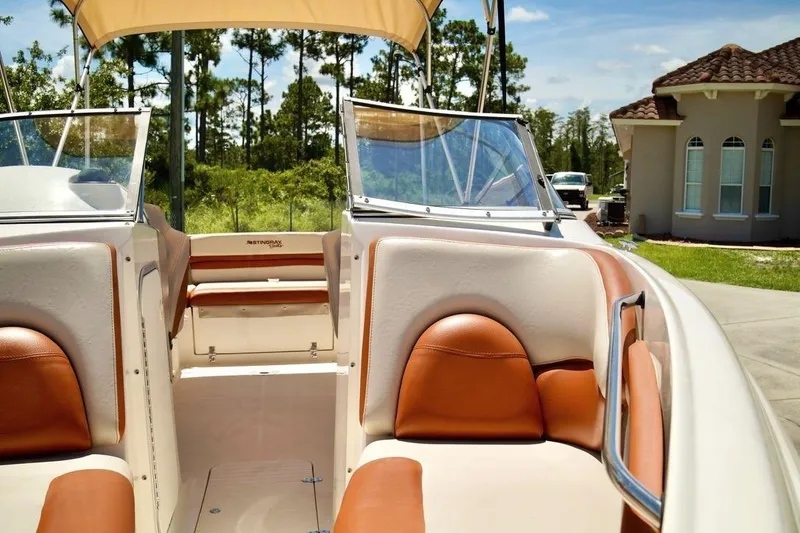 Slide: The Image of 2001 Stingray 240 LS boat interior with tan and brown seating, sunny day. - 11