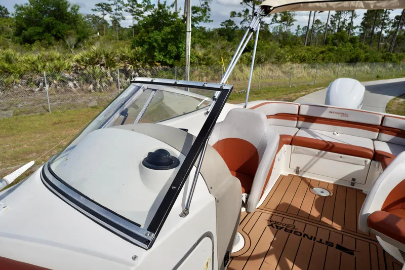 Slide: The Image of 2001 Stingray 240 LS boat interior with seating and steering wheel, surrounded by greenery. - 12
