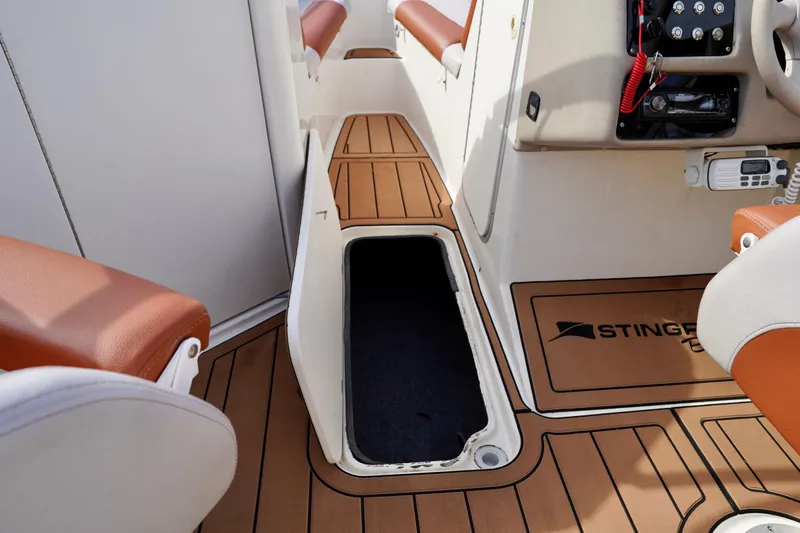 Slide: The Image of Interior of a 2001 Stingray 240 LS boat, featuring tan seating and wood-style flooring. - 17