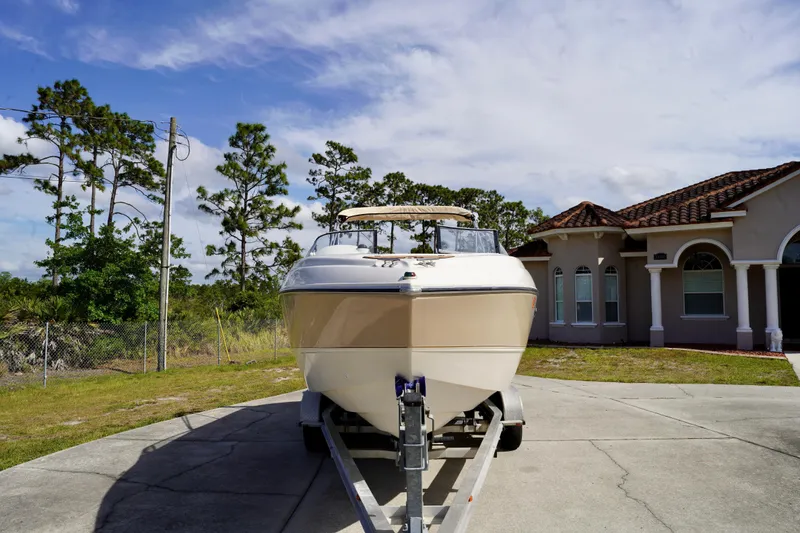Slide: The Image of 2001 Stingray 240 LS boat on trailer, parked in driveway near house and trees. - 2