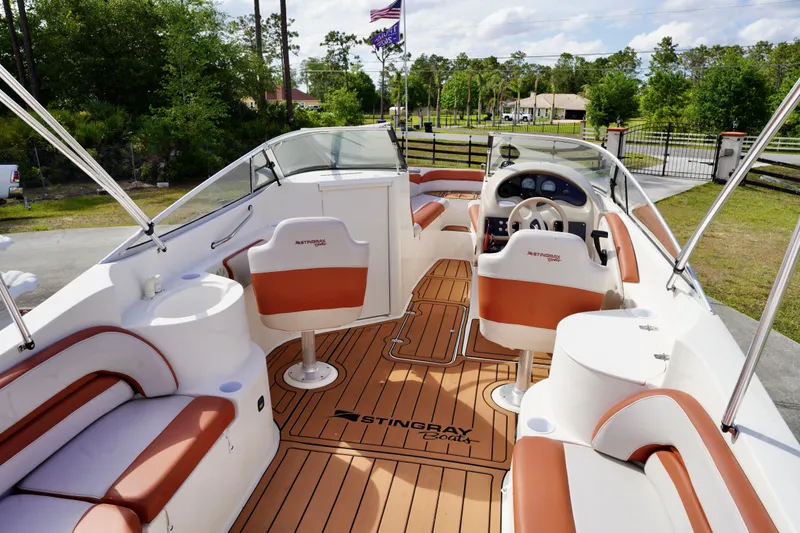 Slide: The Image of 2001 Stingray 240 LS boat interior with tan and white seating, wood-style flooring. - 21