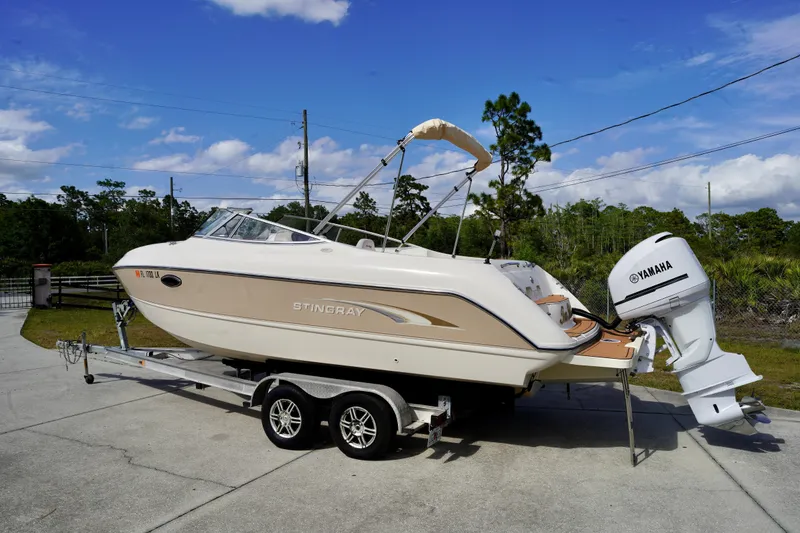Slide: The Image of 2001 Stingray 240 LS boat on trailer with Yamaha outboard motor, parked outdoors. - 3