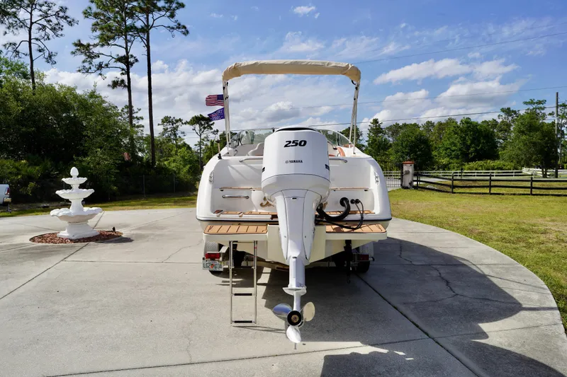 Slide: The Image of 2001 Stingray 240 LS boat with Yamaha 250 engine, parked on driveway with trees and fountain. - 30