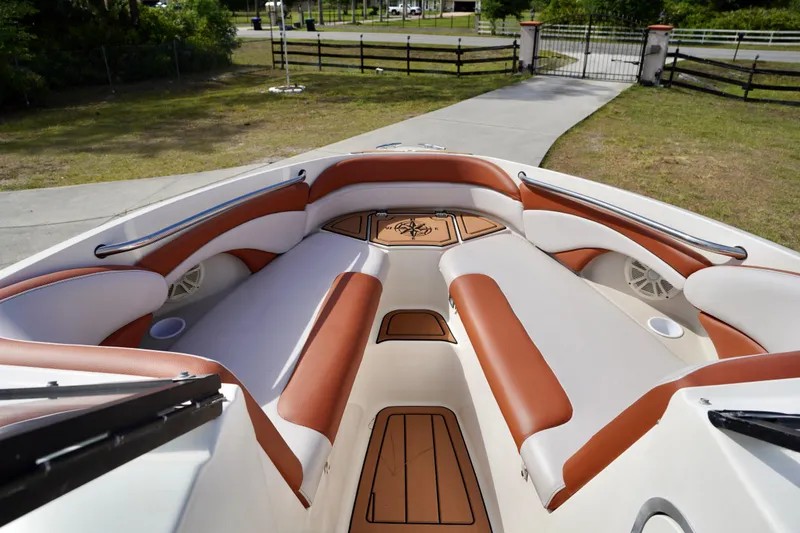 Slide: The Image of 2001 Stingray 240 LS boat interior with brown and white seating, docked outdoors. - 6