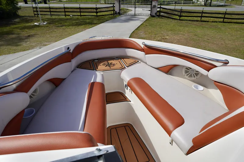 Slide: The Image of 2001 Stingray 240 LS boat interior with brown and white seating, docked outdoors. - 7