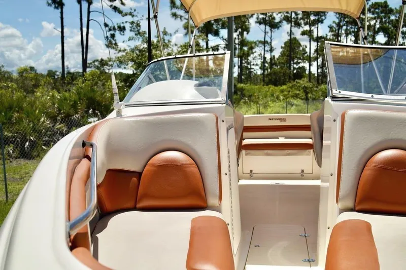 Slide: The Image of 2001 Stingray 240 LS boat interior with tan and orange seating, under a sunny sky. - 8