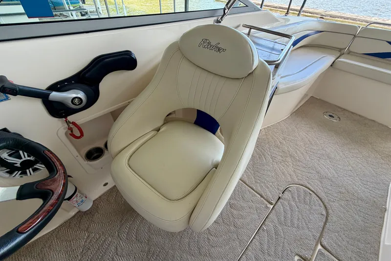Slide: The Image of 2005 Rinker 282 Captiva Bowrider cockpit with steering wheel and beige seating. - 12
